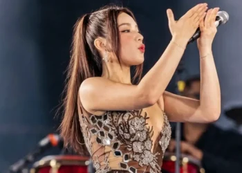 Madaith Carrasco aplaude con un micrófono en mano durante un concierto de la agrupación La Bella Luz.